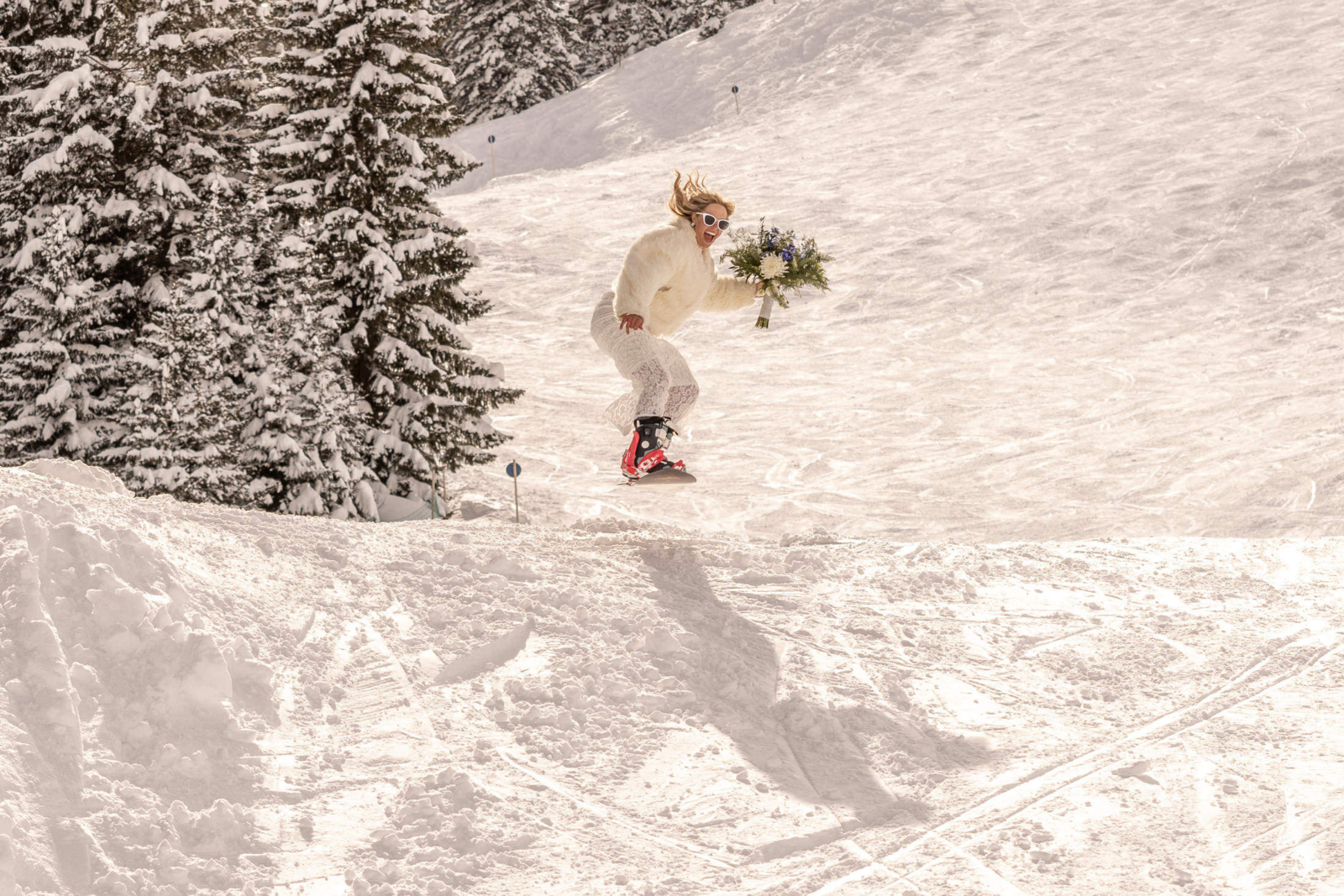 Braut auf dem Snowboard bei der Ski Hochzeit in Lech am Arlberg
