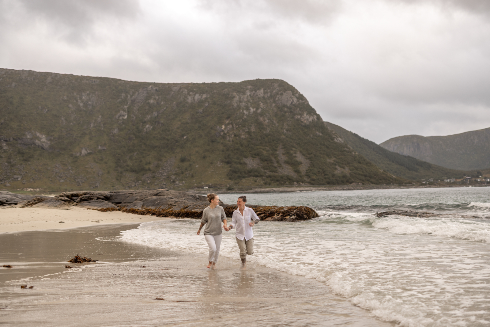 LGBTQ Paar rennt dem Strand entlang in Norwegen